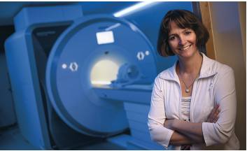 Photo of Dr. Ulrike Dydak standing next to the MRI scanner 