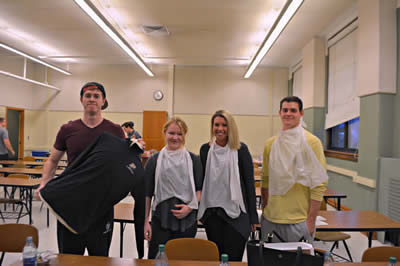 four students wearing plastic napkins