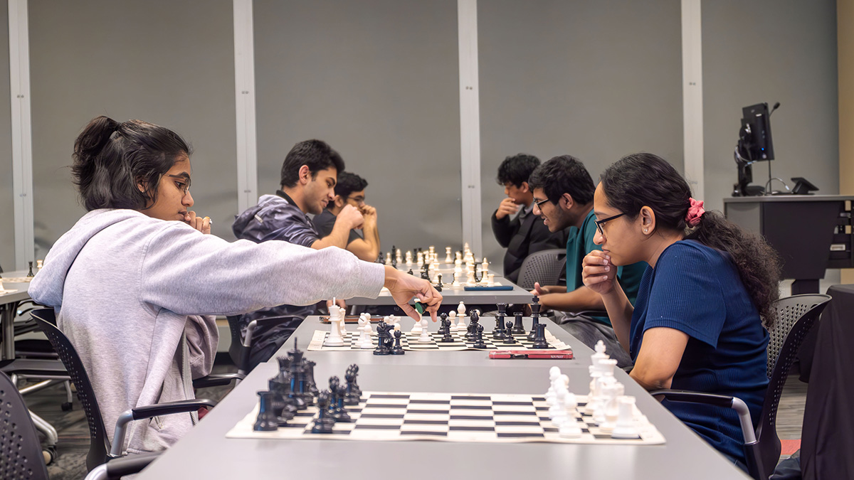 2 female students concentrating on chess match.