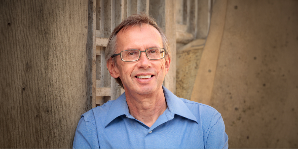 Headshot of person wearing glasses and blue shirt smiling at camera