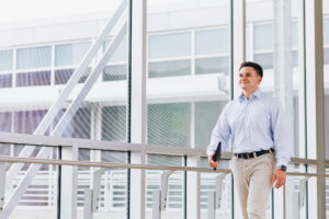 Man walking across an indoor skywalk.