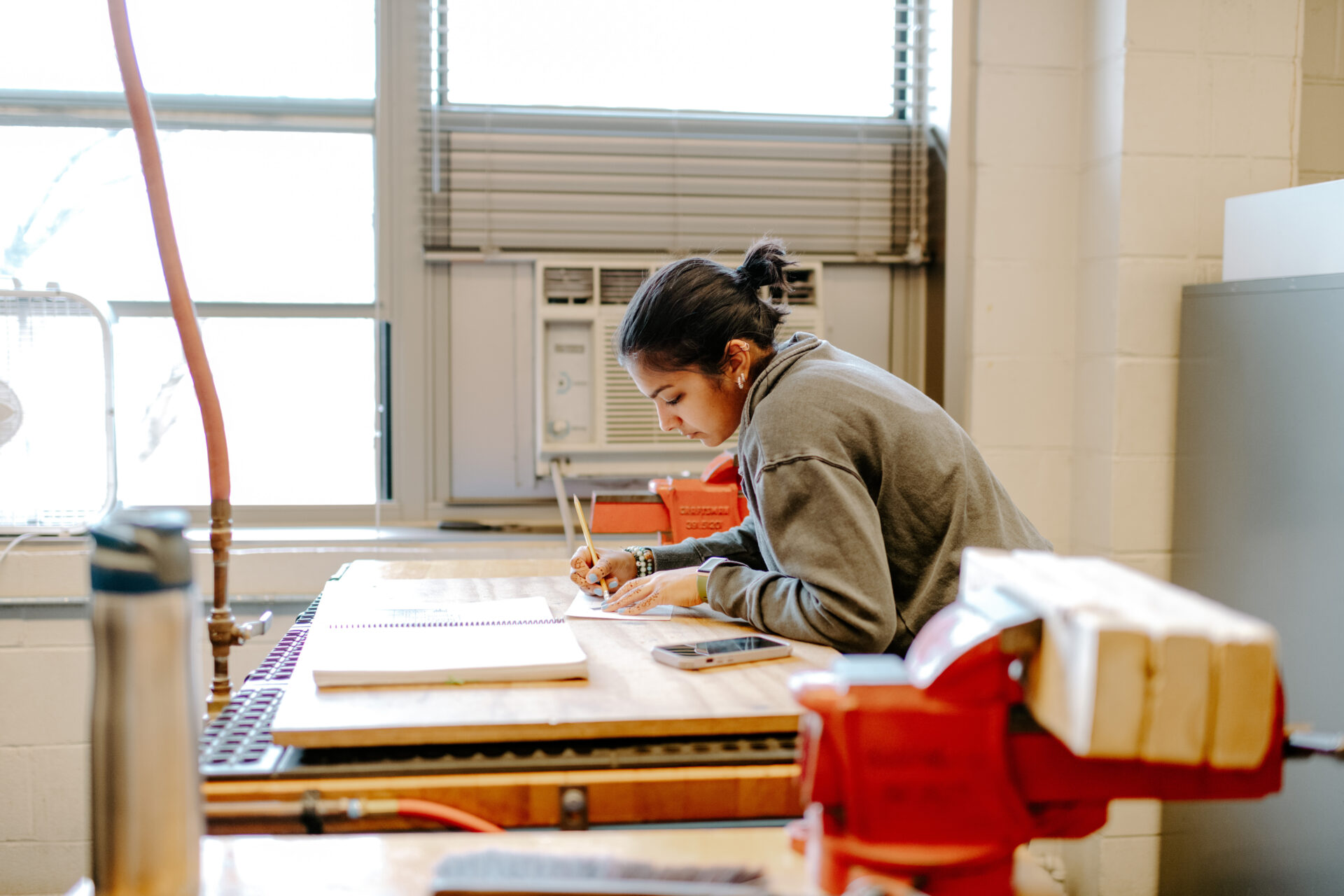 Female working at a workshop table inside a classroom.