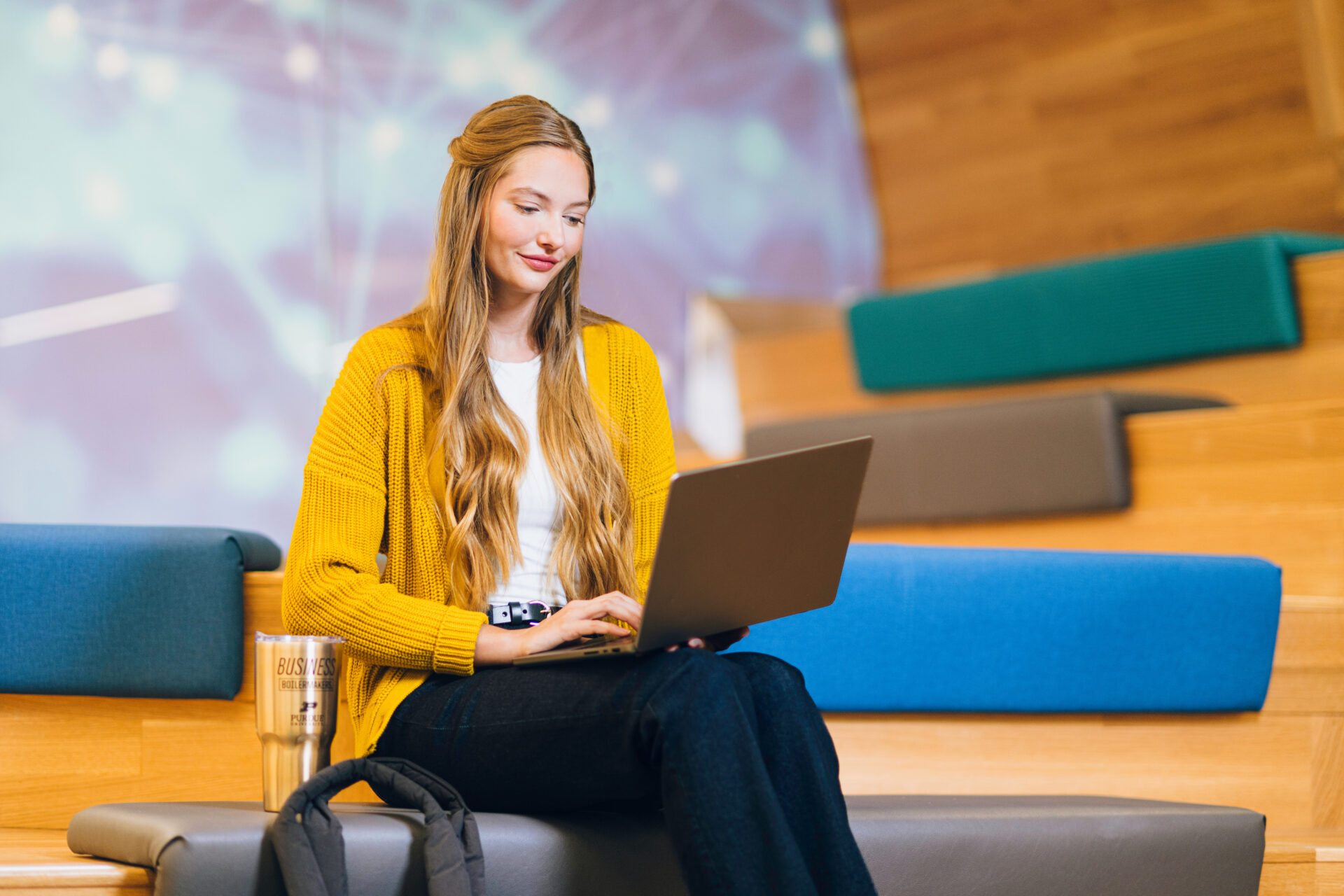 Female sitting in a public area on her laptop.