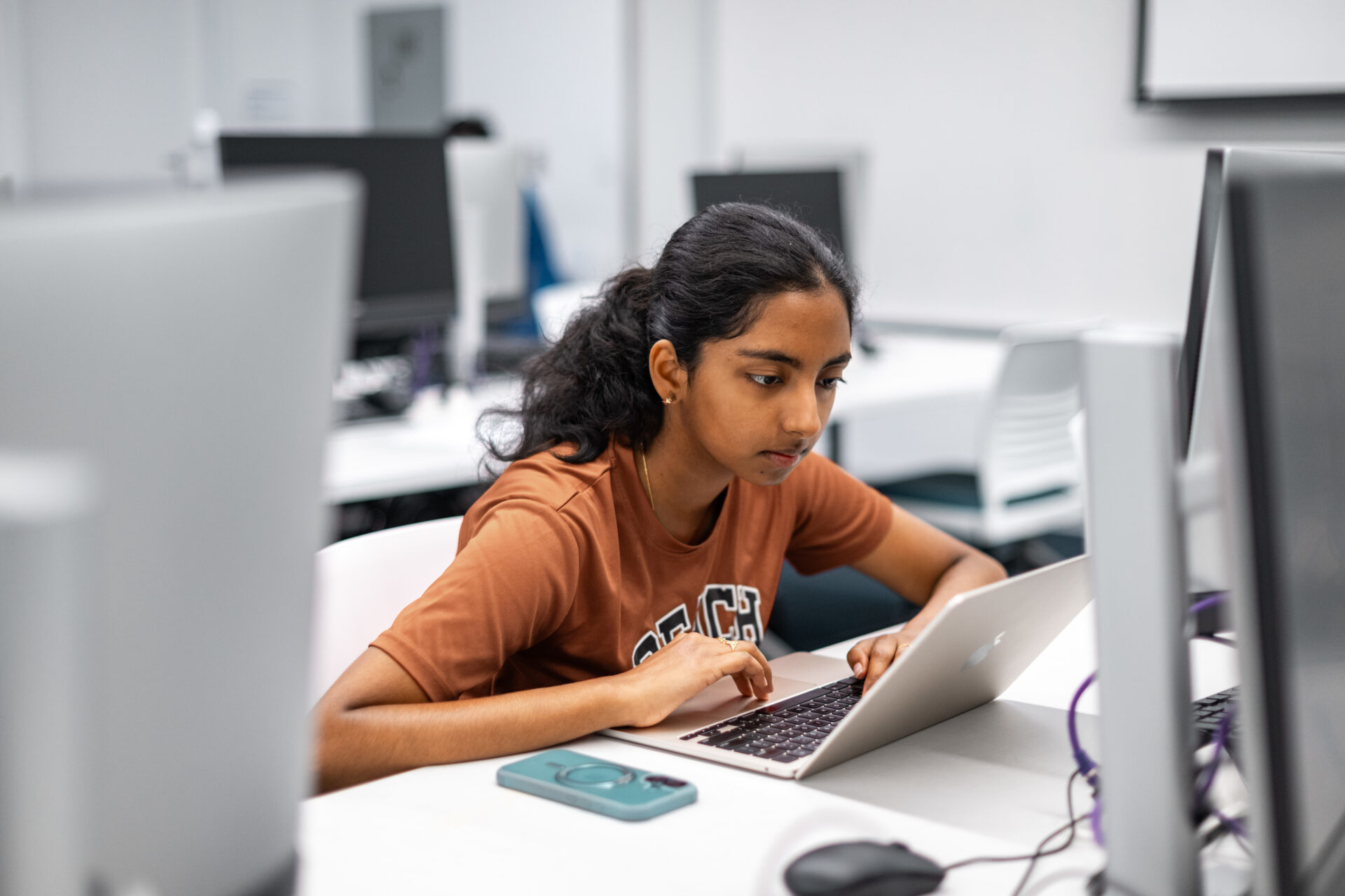 Female sitting in a computer lab working on her laptop.