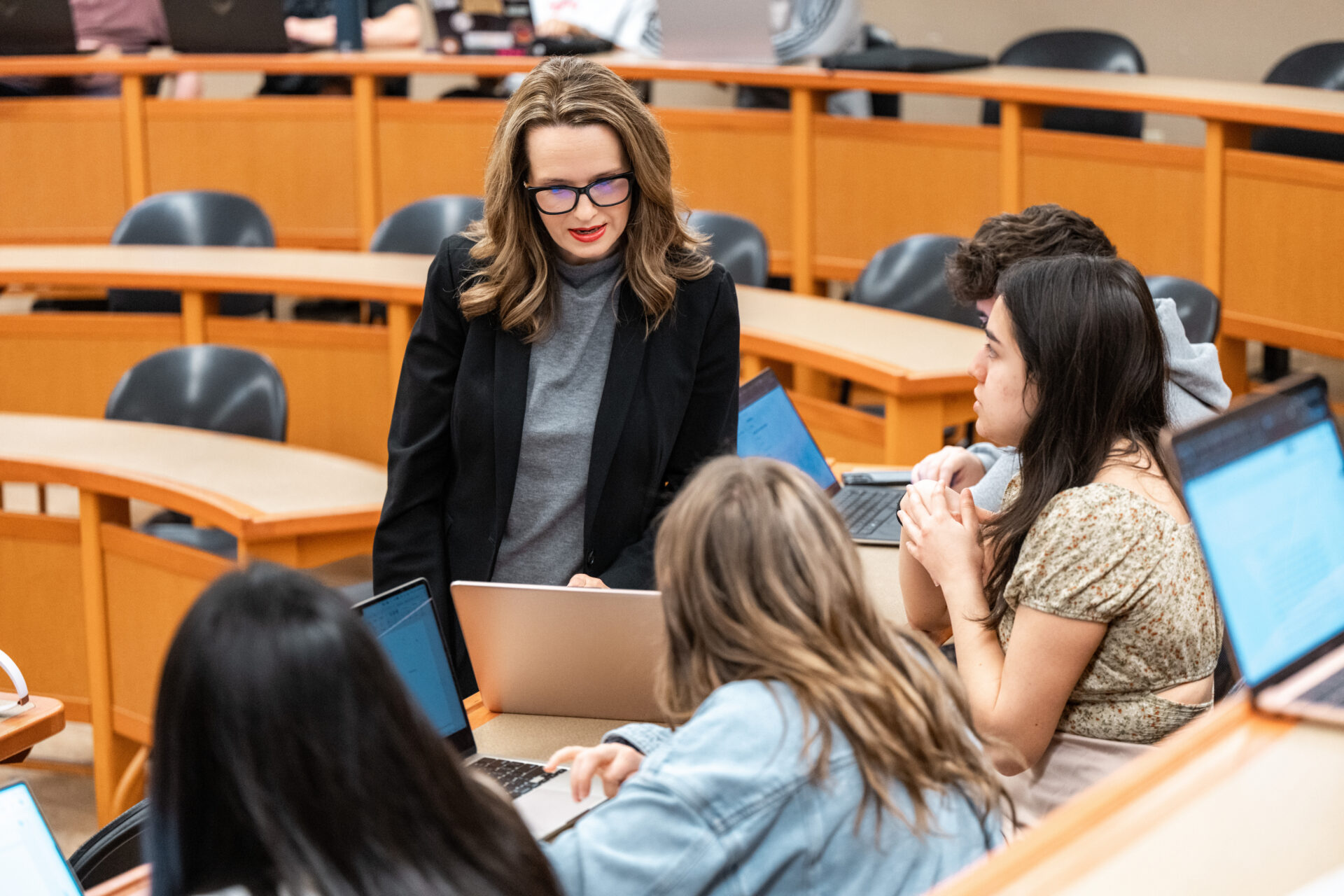 Female lecturer assisting a student in a classroom on their laptop.