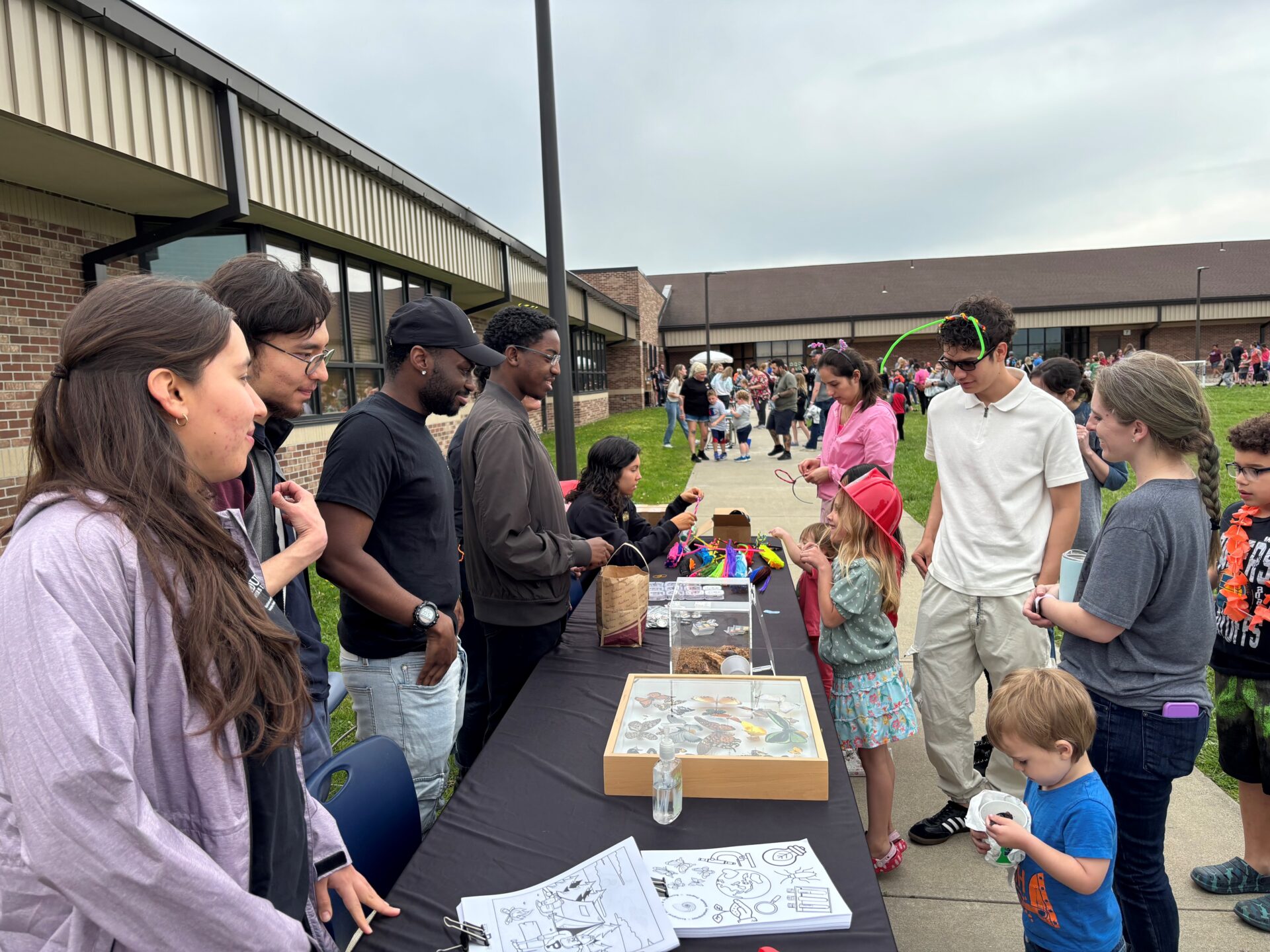 Students outside at information table with bugs.