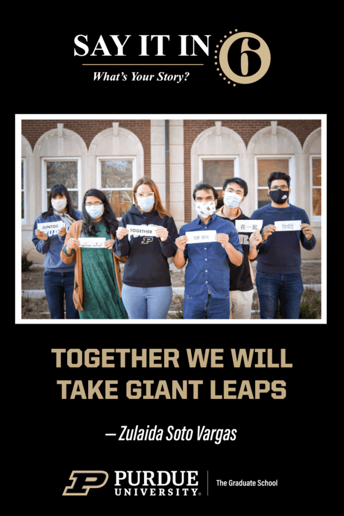 Group of six international students standing in front of a brick building each holding a small sign that states the word "together" in various languages with the caption, "Together we will make giant leaps."