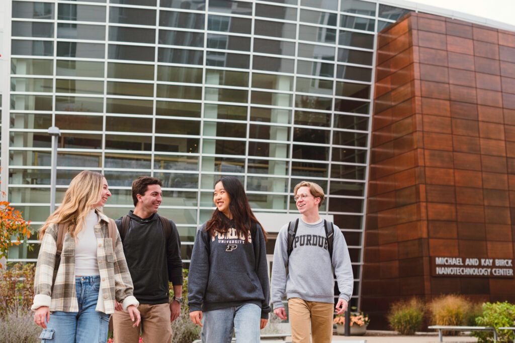 Four students wearing Purdue clothing walking together on campus