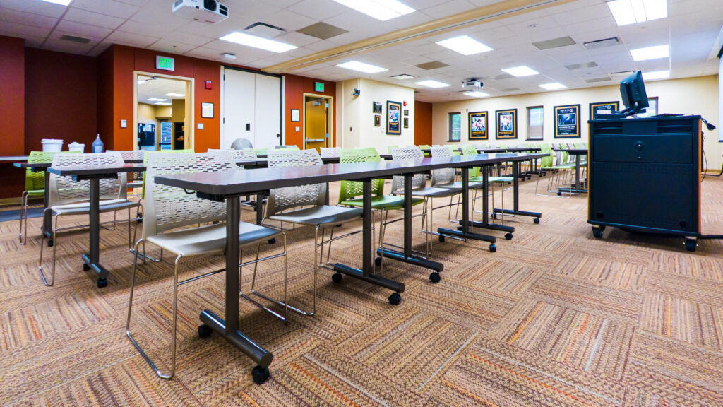 An empty room with tables, chairs, and screens