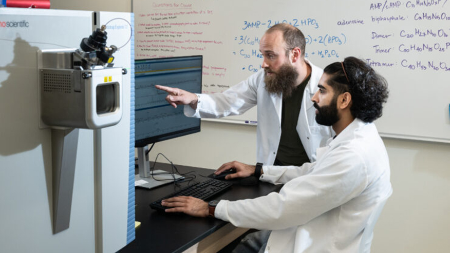 Student updates his research activity with professor in a lab.