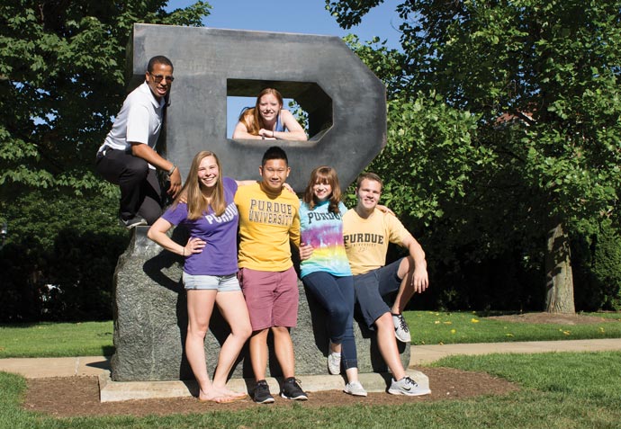 students posing next to block P sculpture