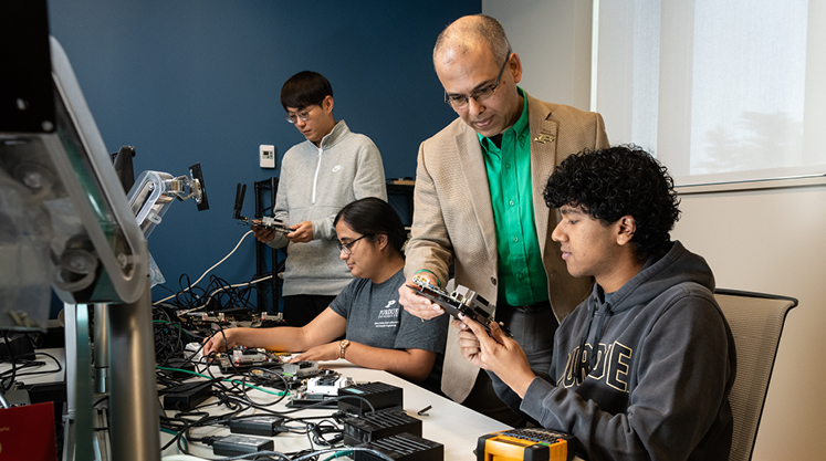 Purdue students work in a lab with a professor and inspect materials.