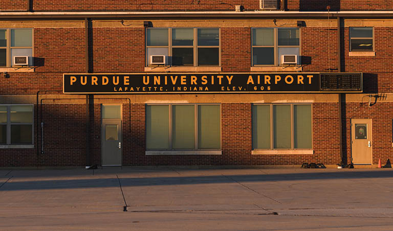 A large sign on a brick building that states Purdue University Airport.