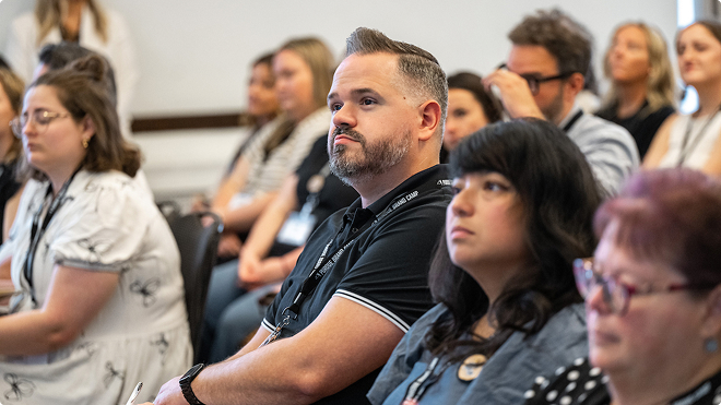 Audience members listening intently during a campus presentation.