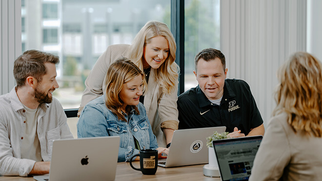 Coworkers collaborating around a laptop in an office