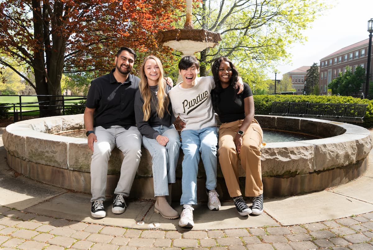 purdue students sitting together by a campus fountain