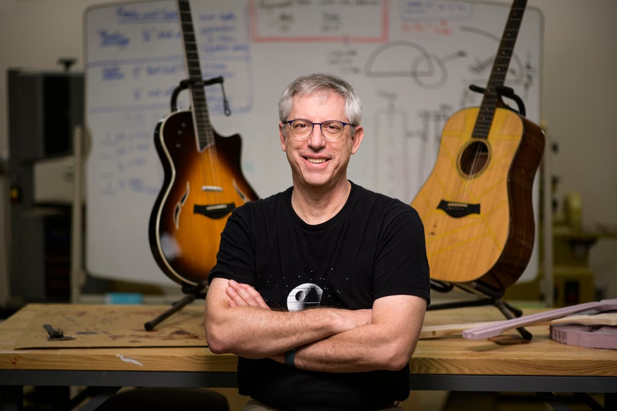 man posing with guitars in a workshop