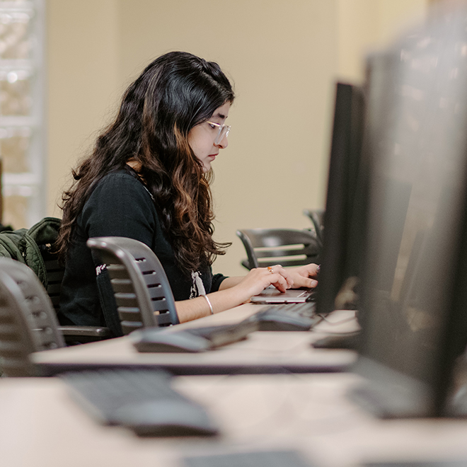 Student typing at desktop computer