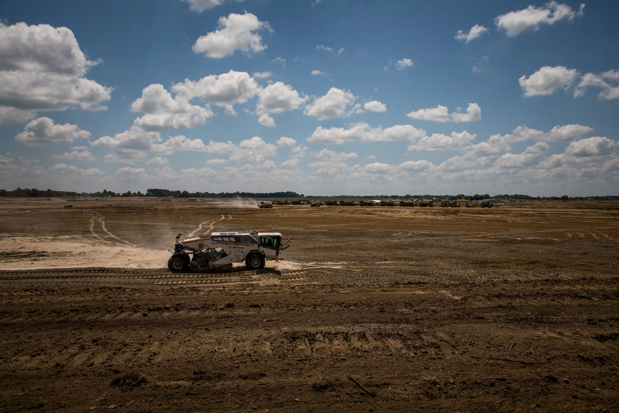 Construction vehicle grading an open field.