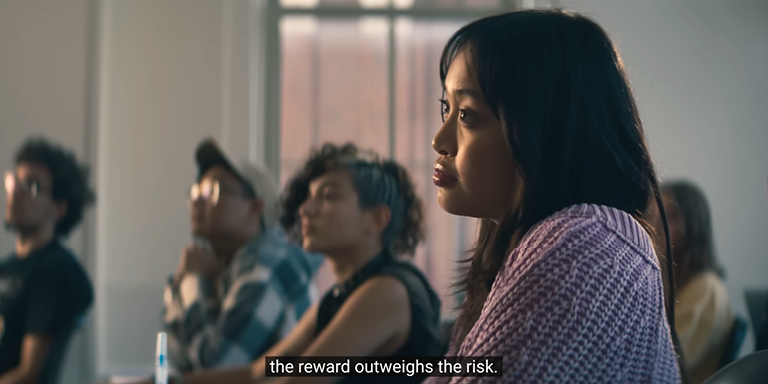 Student sitting in classroom with video caption.