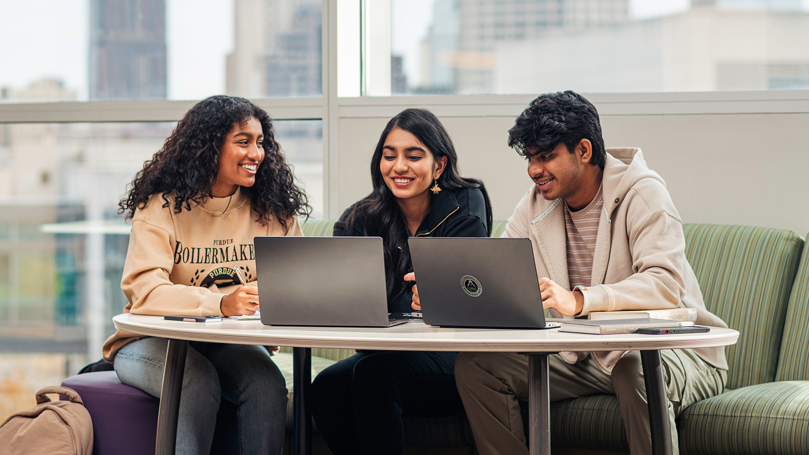 Three Purdue University students sitting at a table working on laptops