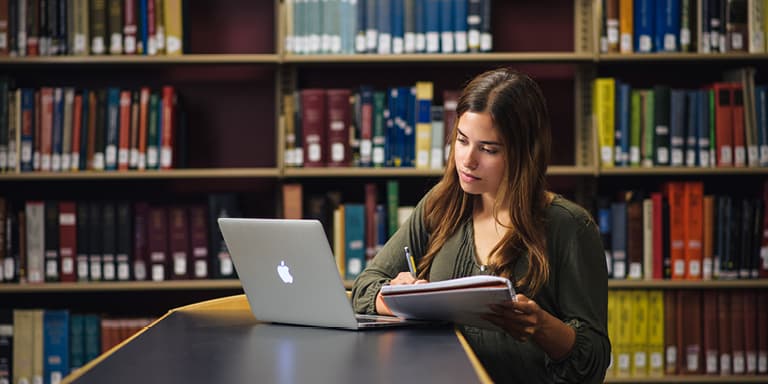 Student studying with laptop in a library.