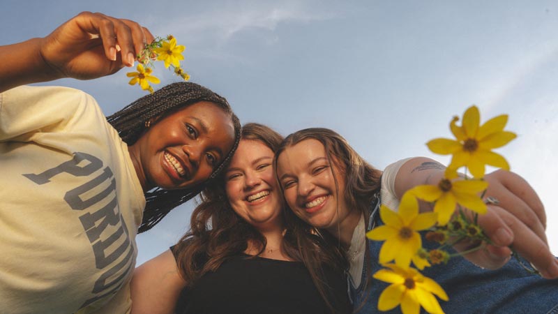 Students, smiling, holding flowers
