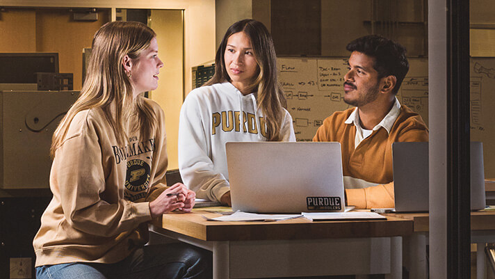 Three students working at a table.