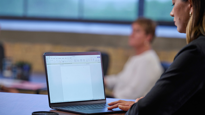 Woman using a laptop in an office meeting.