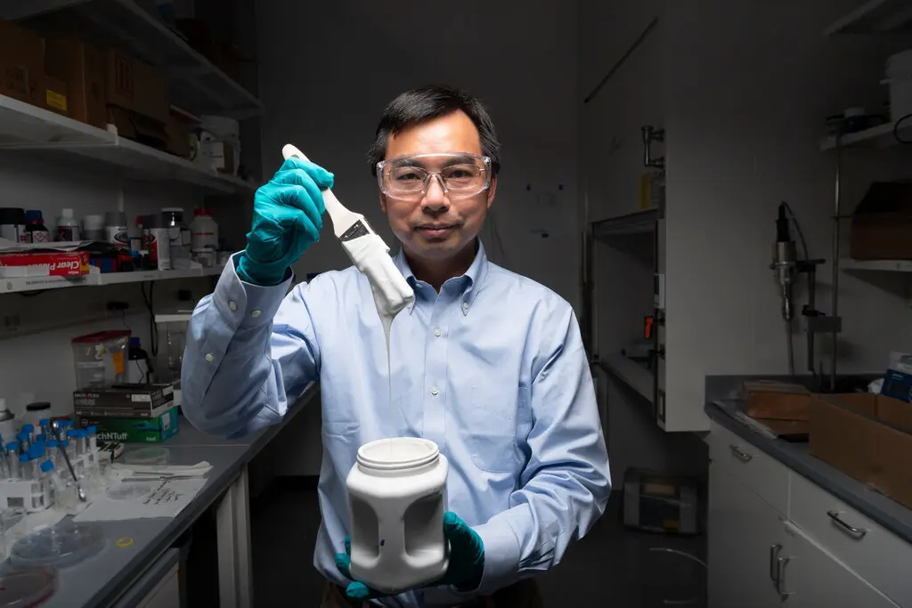 Man in lab holding white paint.