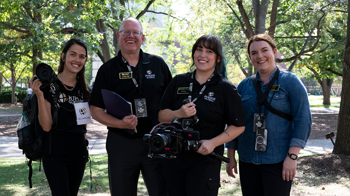 Purdue Global photography crew smiling outdoors.