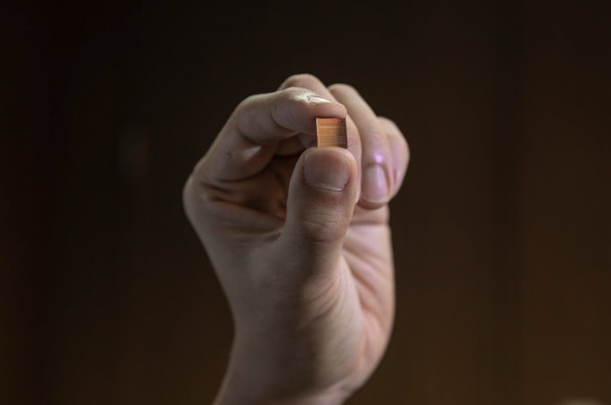 Hand holding a tiny semiconductor computer chip.