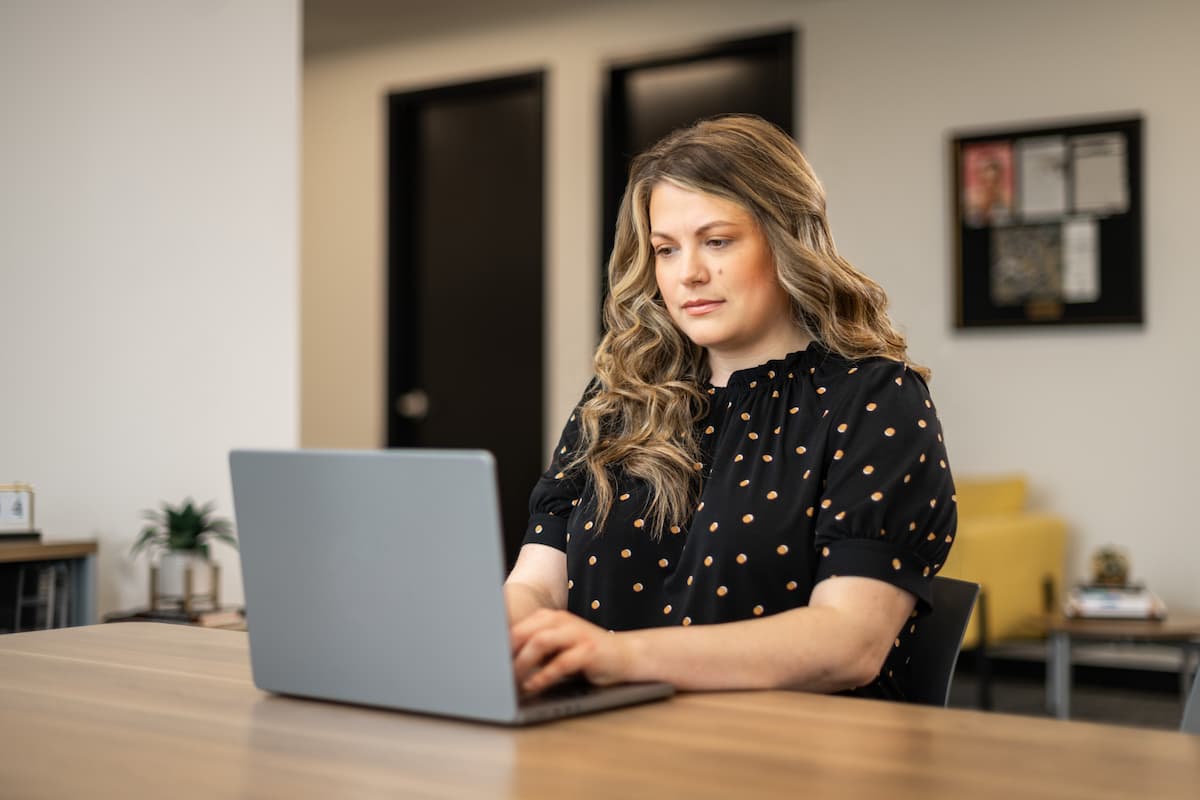 Woman working on a laptop during an office meeting.
