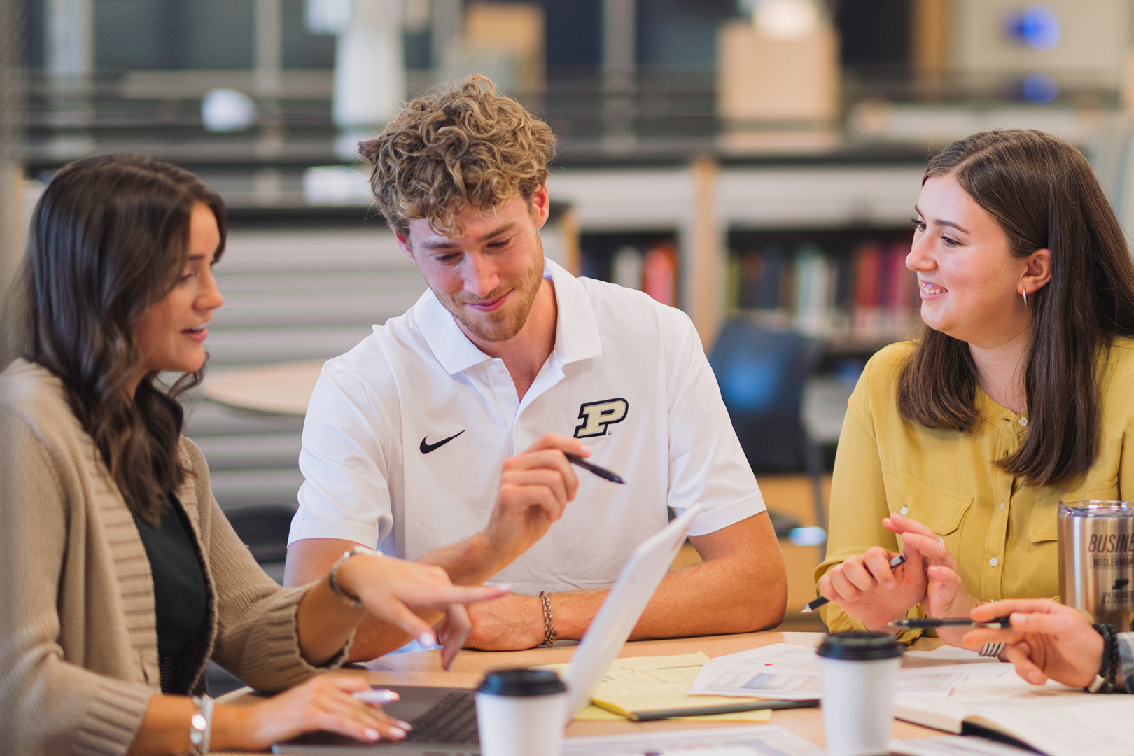 Male in Purdue shirt sitting at table with two females