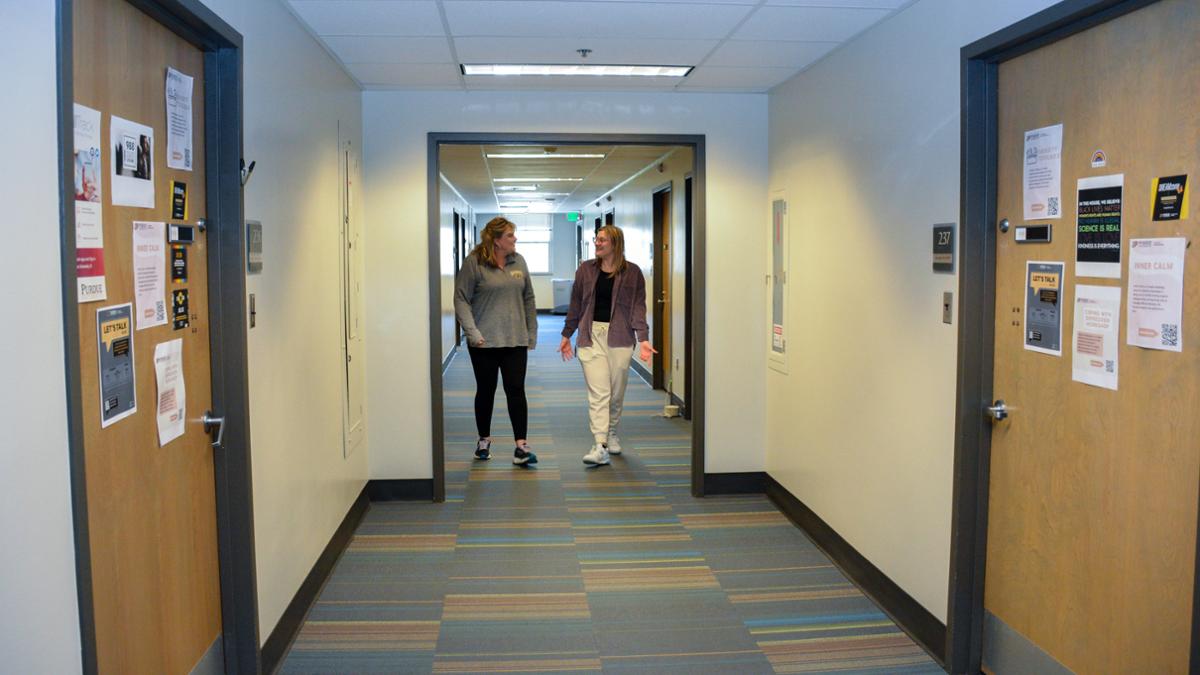 Student and CAPS Clinician walking down the corridor at CAPS talking. 
