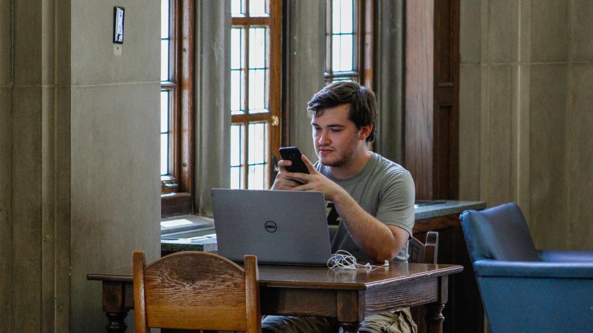 Student studying at PMU, looking at his laptop.