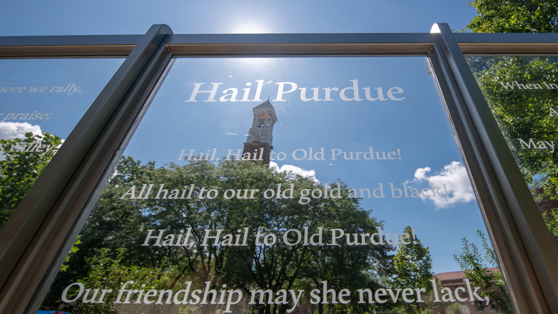 Hail Purdue sign with a view of the Bell Tower through its glass.