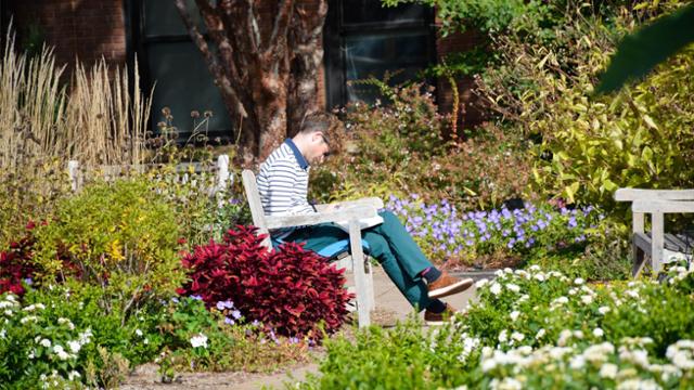 A student sitting on a bench outside writing in a notebook.