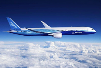 Commercial passenger airplane flying above clouds, representing aerospace manufacturing and advanced aircraft structures.