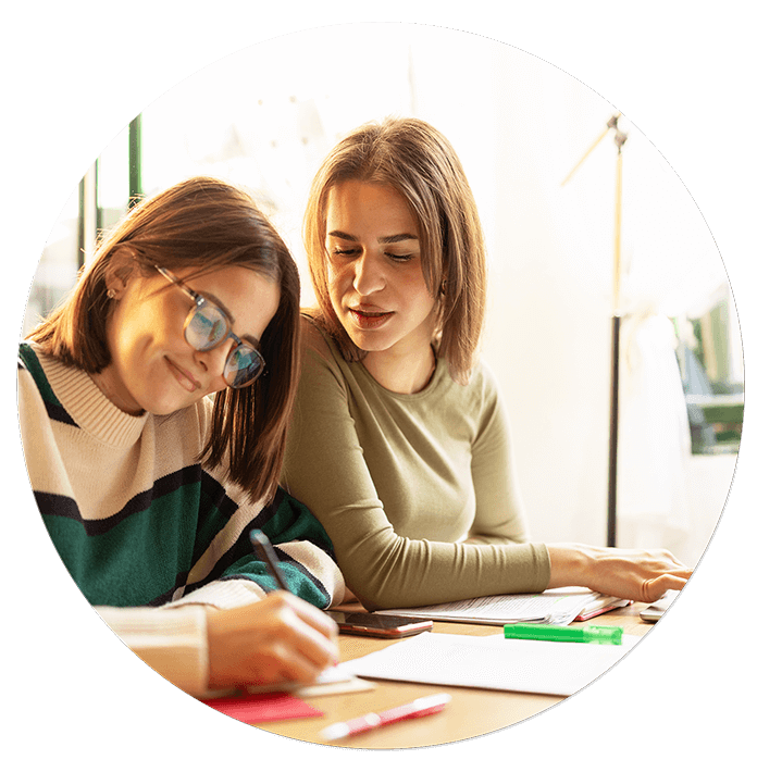 Teenage girl and mother writing at desk.