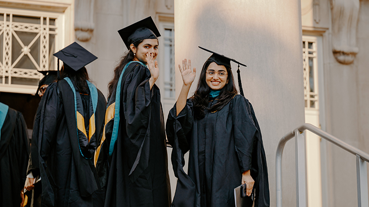 Graduates standing outside of Elliott Hall of Music waving