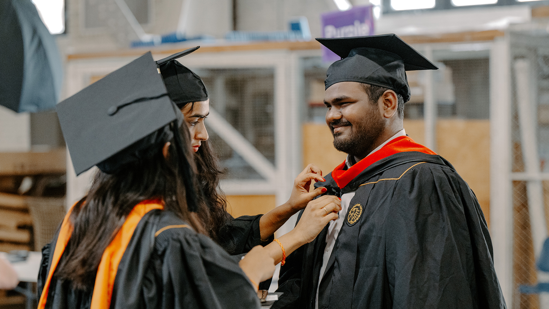 Graduate preparing for commencement by getting his hood adjusted