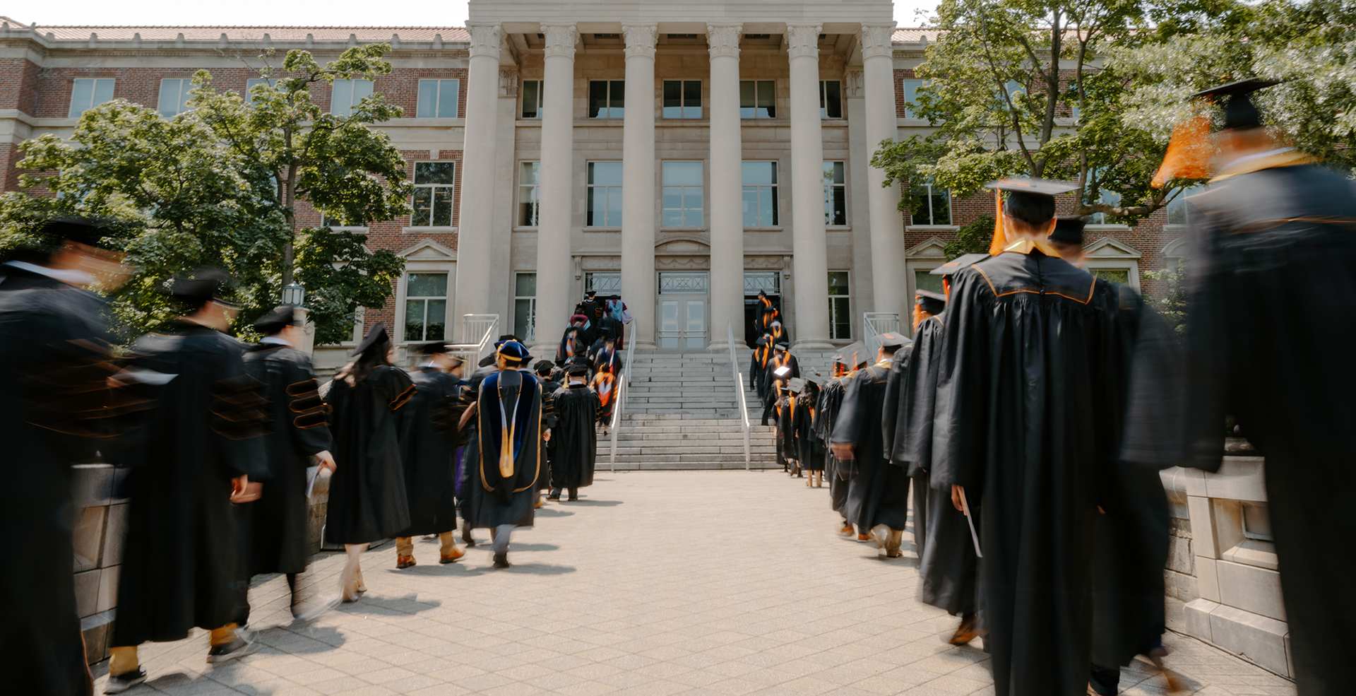 The procession of students cross Engineering Mall and up the steps and into Hovde Hall.