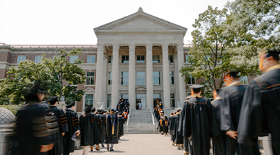 Graduates walking up the steps of Hovde Hall before graduation commencement