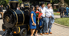 Family posing in front of Purdue Extra Special train on graduation day
