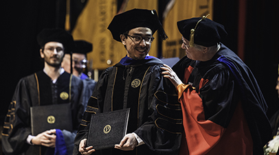 A faculty member hoods the graduate