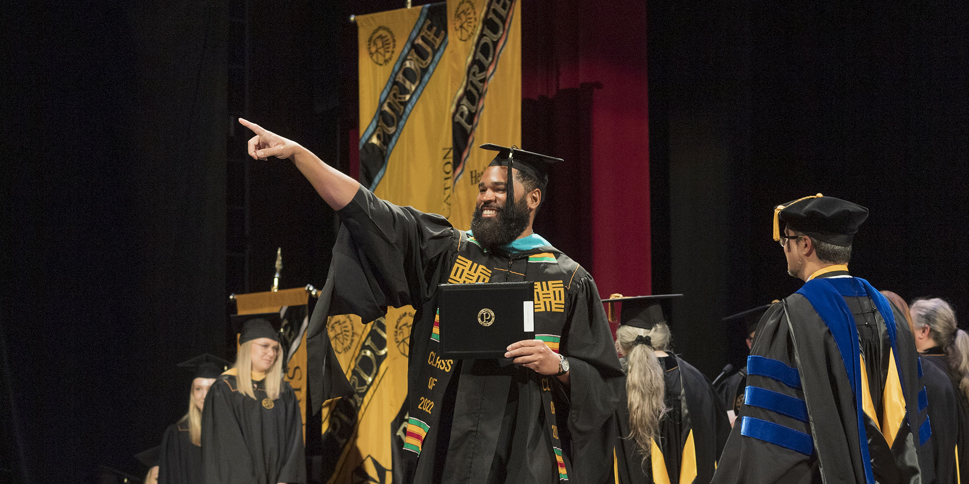 Graduate on stage  pointing at the crowd after receiving his diploma