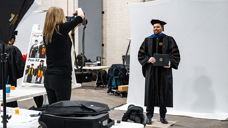 Graduate posing for professional photographer in the Armory before Purdue Commencement