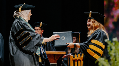 Graduate receiving diploma on stage from a faculty member at Purdue University commencement