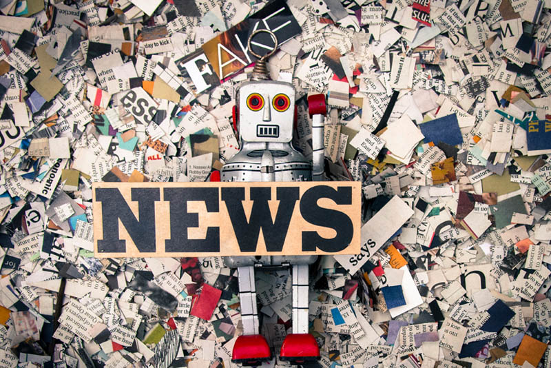 Image of a toy robot, news clippings, and Fake News text